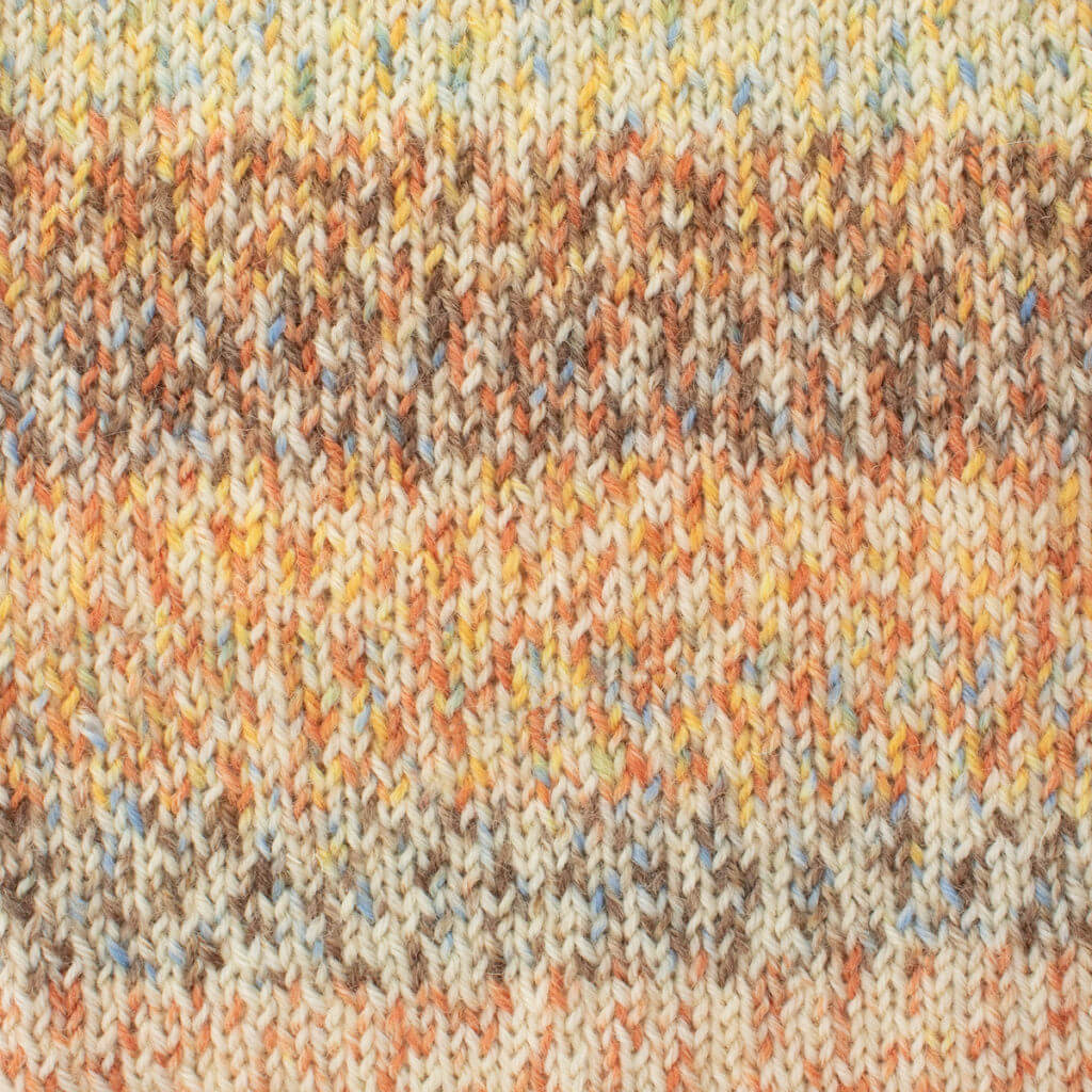 Close-up of West Yorkshire Spinners Signature 4ply, Small Tortoiseshell knitted fabric with a multicoloured pattern in earth tones, including beige, brown, and orange, creating a warm, cozy texture.