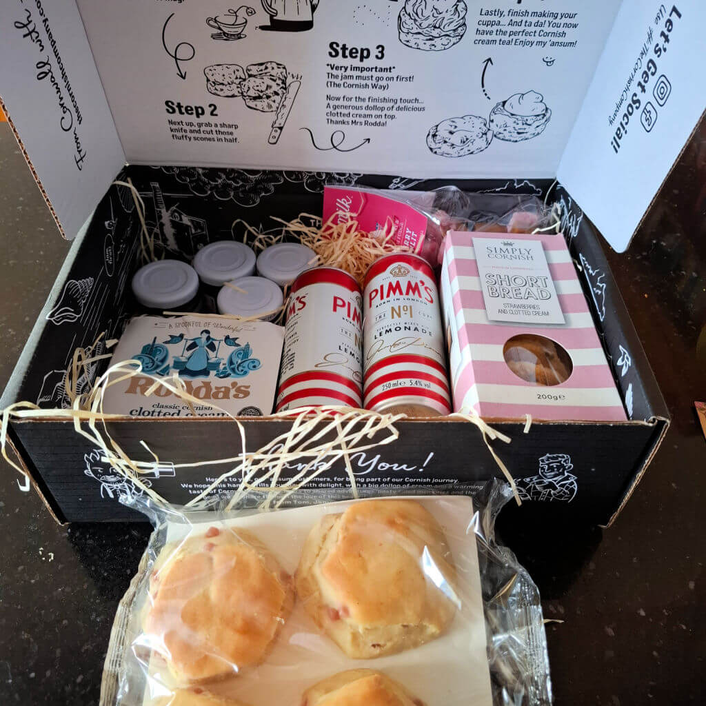 Gift box with scones, clotted cream, Pimm's cans, and shortbread. Decorated with hay, box has step-by-step serving instructions printed inside.