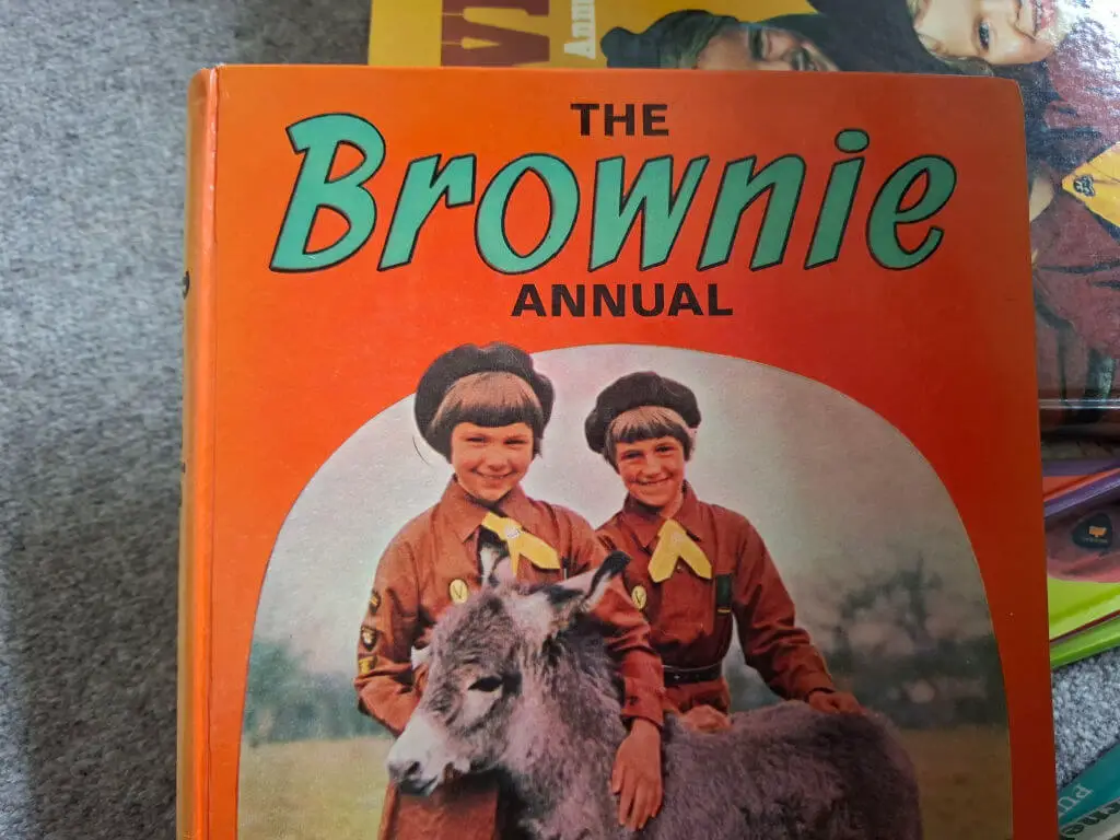 Cover of "The Brownie Annual" shows two smiling children in brown uniforms with yellow scarves petting a small donkey, set against an orange background.