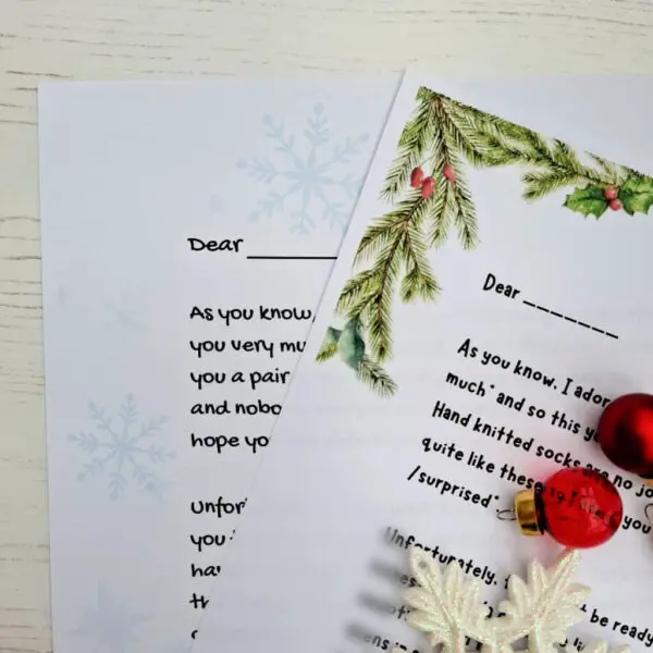 Close-up of two festive letters, each beginning with "Dear," adorned with holly and snowflake designs. Red ornaments and a white snowflake decoration add a cheerful holiday vibe.