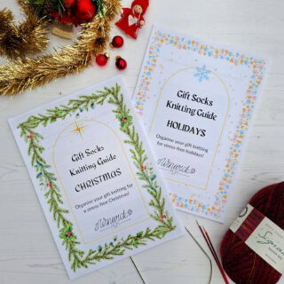 Two Winwick Mum knitting guides titled 'Gift Socks Knitting Guide: Christmas' and 'Holidays' with festive designs and needles on a white surface.