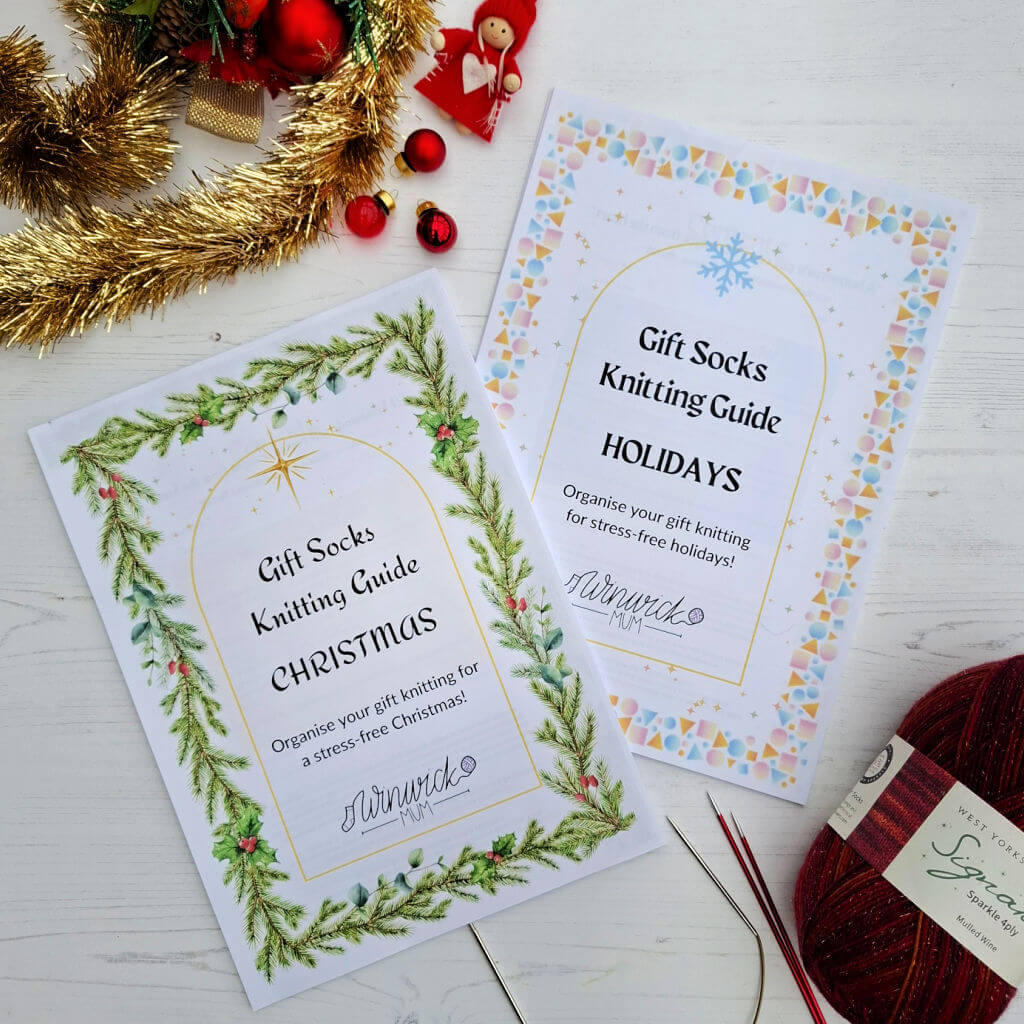 Two Winwick Mum knitting guides titled 'Gift Socks Knitting Guide: Christmas' and 'Holidays' with festive designs and needles on a white surface.