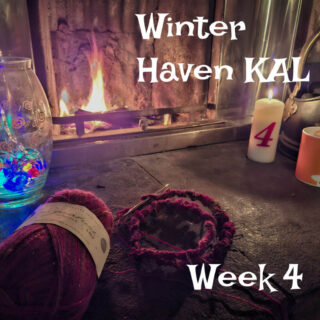 Cosy scene with knitting supplies, colourful yarn in front of a warm fireplace. A lit candle marked "4" and vibrant glass decor set a relaxing winter mood.