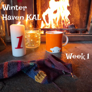 Cosy scene by a fireplace with an orange mug, a lit candle marked "1," a partly-knitted sock, and warm lighting. Text: "Winter Haven KAL, Week 1."