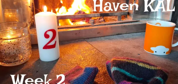 Cosy scene by a lit fireplace with striped knit socks, a red-numbered candle, and an orange mug. Text reads, "Winter Haven KAL, Week 2."
