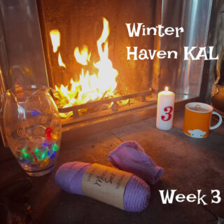 Cosy fireplace scene with yarn, a colourful vase, a lit candle marked “3,” and an orange mug. Text reads “Winter Haven KAL Week 3,” conveying warmth.