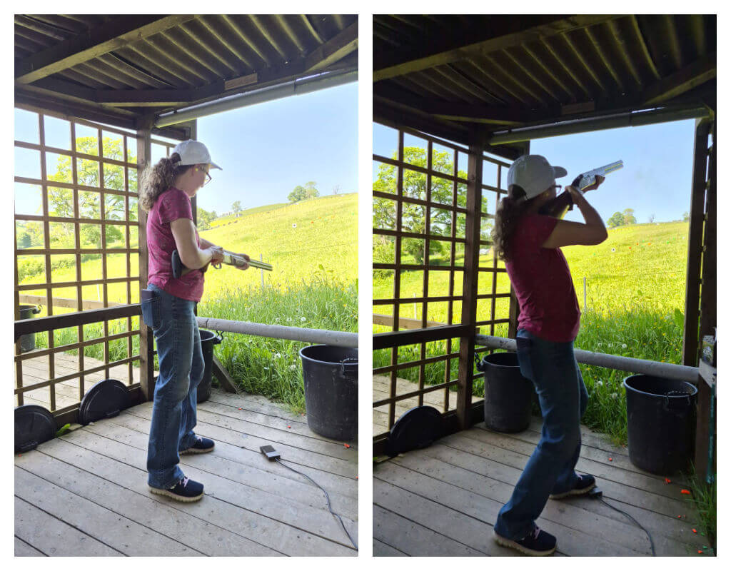 A woman in a white cap and red shirt practices clay pigeon shooting. She holds a shotgun, aiming at targets, surrounded by green fields and wooden lattice.