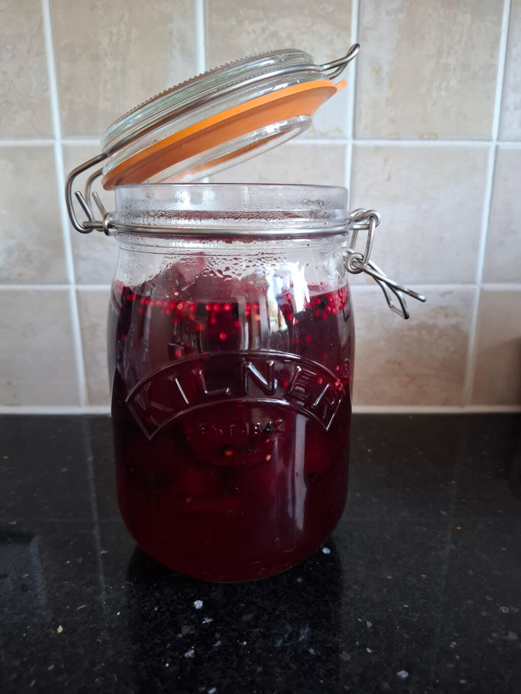 Pickled beetroot in vinegar in a large jar on a kitchen counter.  The lid is open to let the beetroot cool.